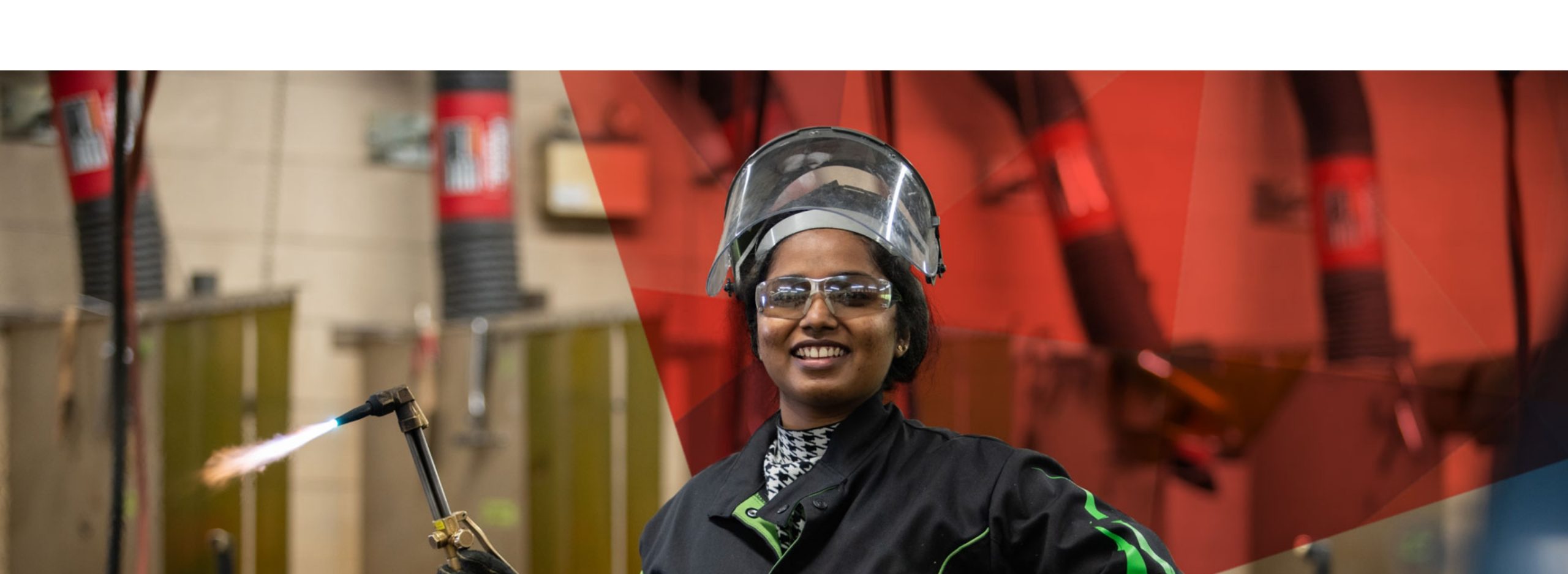 A female tradeswoman smiling holding a welding tool
